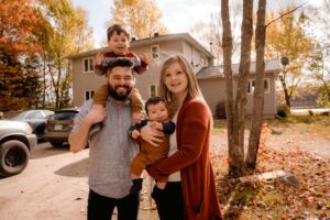 young family in front of their cars and home